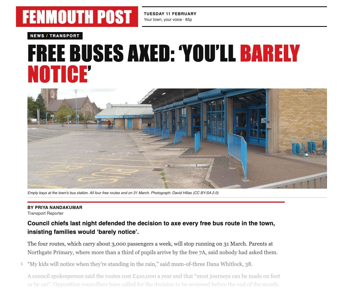 The top of a printed local tabloid page, the ‘Fenmouth Post’, with a red masthead: a ‘News / Transport’ tag; a capital headline ‘Free buses axed: “you'll barely notice”’, with ‘barely notice’ in red; a wide photograph of an empty bus station, its bays and blue railings deserted, captioned ‘Empty bays at the town's bus station. All four free routes end on 31 March.’; the byline Priya Nandakumar, Transport Reporter; then the bold opening sentence and the report fading out at the foot of the clipping.