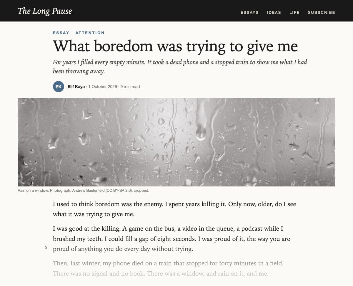 The top of an essay on ‘The Long Pause’, an online essay magazine with a black site bar: the tag ‘Essay · Attention’; the headline ‘What boredom was trying to give me’; an italic standfirst, ‘For years I filled every empty minute. It took a dead phone and a stopped train to show me what I had been throwing away.’; the byline Elif Kaya, 1 October 2026, 9 min read; a wide grey photograph of raindrops running down a window; then the line-numbered opening, ‘I used to think boredom was the enemy…’, fading out at the foot of the clipping.